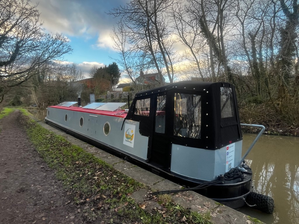 Side view of Narrowboat And Away moored up canalside opposite the pub