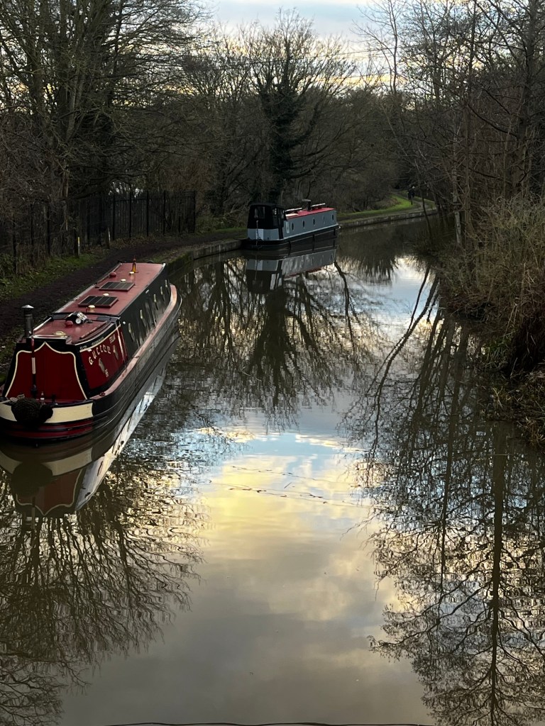 View from a bridge of Narrowboat And Away moored in front of another narrowboat